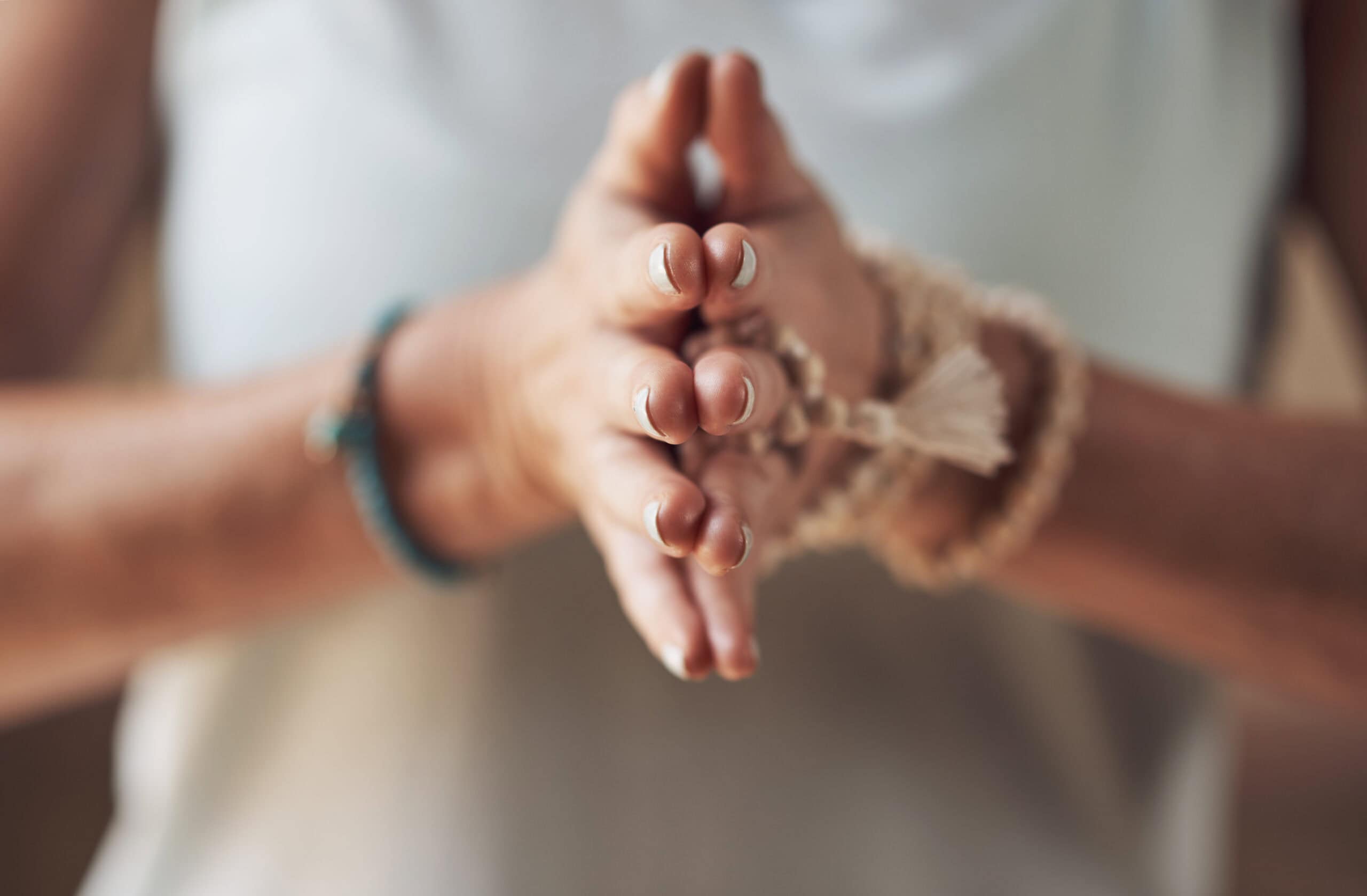 Cropped shot of an unrecognizable woman standing with her palms together while meditating indoors.